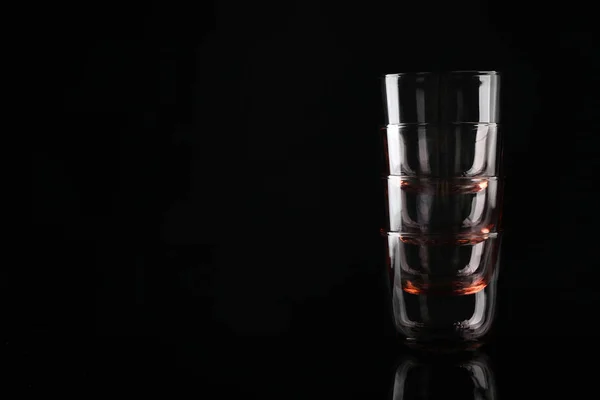 Stos pustych kolorowych okularów whisky na czarnym tle, miejsce na tekst — Zdjęcie stockowe