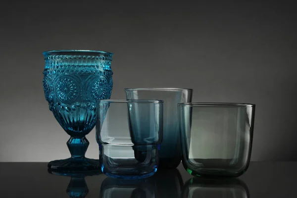 Ensemble de différents verres vides colorés sur la table sur fond gris — Photo