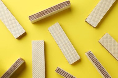 Tasty wafer sticks on yellow background, flat lay. Sweet food clipart
