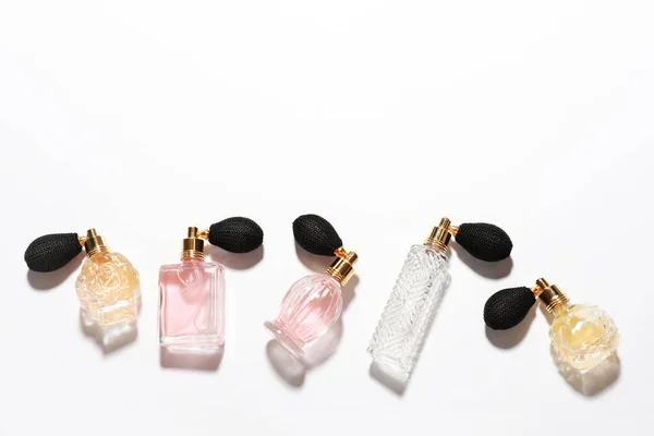 Différentes bouteilles de parfum élégantes sur fond blanc, vue de dessus — Photo