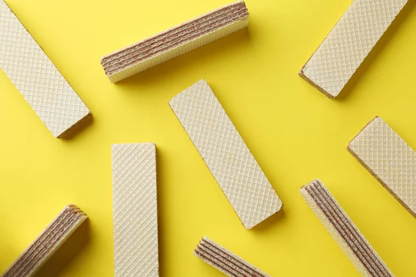 Palitos de wafer saborosos no fundo amarelo, flat lay. Comida doce — Fotografia de Stock