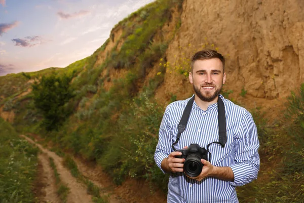 Fotografo di sesso maschile con fotocamera professionale tra verdi colline — Foto Stock