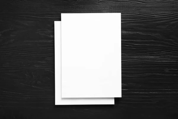 Stack of blank paper sheets for brochure on black wooden background, top view. Mock up — Stock Photo, Image