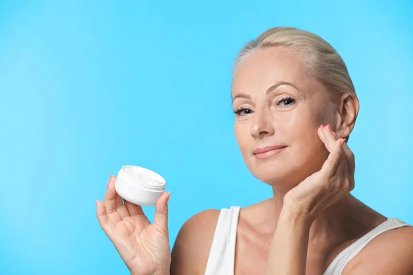 Retrato de mujer madura hermosa con la piel perfecta celebración tarro de crema sobre fondo azul claro —  Fotos de Stock