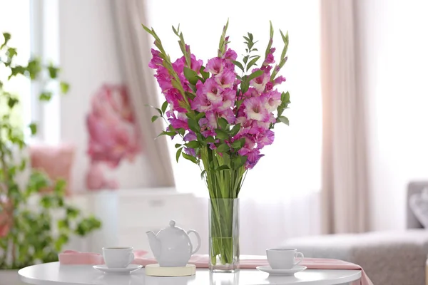 Vas dengan indah bunga gladiolus merah muda di meja kayu di ruang tamu — Stok Foto