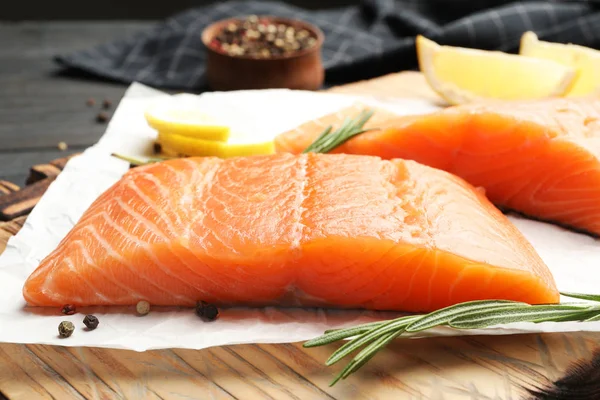 Wooden board with tasty salmon fillet on dark table, closeup Royalty Free Stock Images