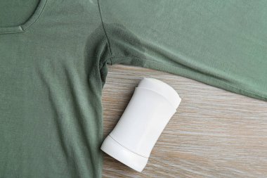 Ahşap arka planda leke ve deodorant içeren giysiler, üst görünüm