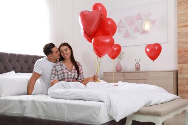 Yatak odasında kalp şeklinde balonlar ile güzel çift