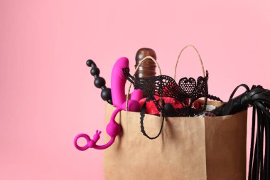 Pembe arka planda farklı seks oyuncakları ile Kağıt alışveriş çantası