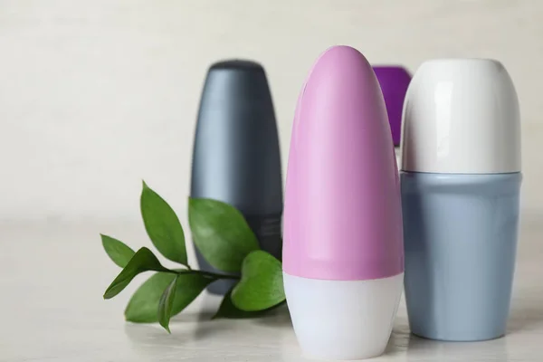 Açık gri masada doğal roll-on deodorantlar ve yeşil bitki — Stok fotoğraf
