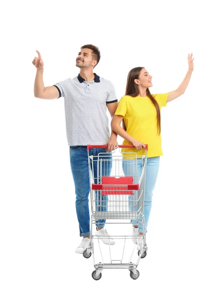 Junges Paar mit leerem Einkaufswagen auf weißem Hintergrund — Stockfoto