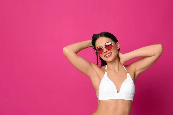 Hermosa joven en bikini blanco con gafas de sol sobre fondo rosa. Espacio para texto —  Fotos de Stock