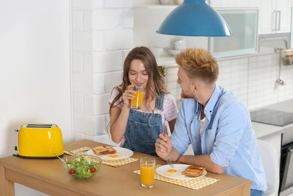 Mutfaktaki masada kahvaltı eden mutlu genç çift. — Stok fotoğraf