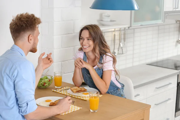 Boldog fiatal pár reggelizik az asztalnál a konyhában — Stock Fotó