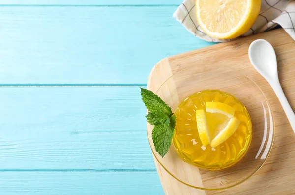 Deliciosa jalea amarilla con rodajas de limón y menta en la mesa de madera azul claro, puesta plana. Espacio para texto — Foto de Stock