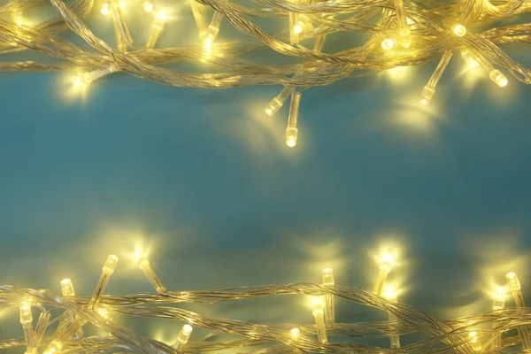 Leuchtende Weihnachtsbeleuchtung auf blauem Hintergrund, Draufsicht. Raum für Text — Stockfoto