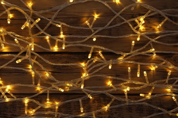 Glowing Christmas lights on wooden background, top view — Stock Photo, Image