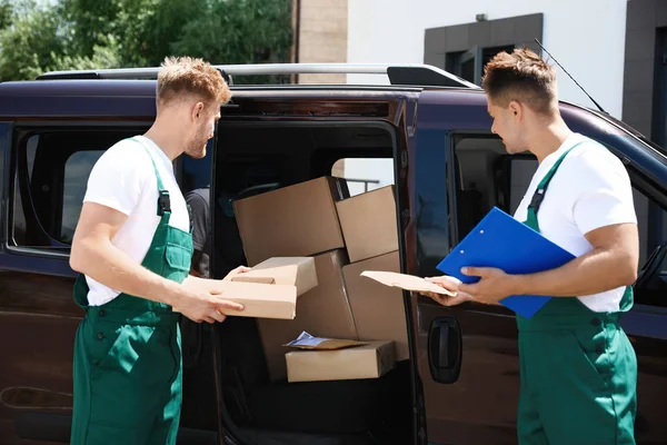 Young couriers with parcels near delivery car outdoors — Stock Photo, Image