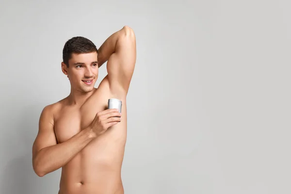 Fiatal férfi alkalmazó dezodor a hónalban a fény hátterét. Szóköz a szöveghez — Stock Fotó