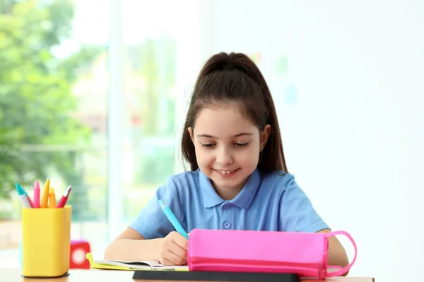教室の机で宿題をしている小さな女の子。学校文房具 — ストック写真