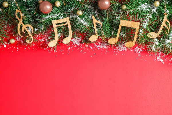 Composizione laica piatta con decorazioni natalizie e note musicali su sfondo rosso, spazio per testo — Foto Stock