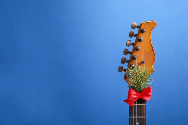 Guitarra con lazo rojo y rama de abeto sobre fondo azul, espacio para texto. Música navideña —  Fotos de Stock