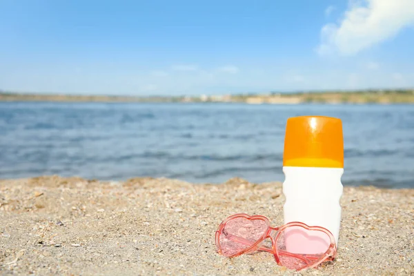 Fles Zonnebescherming bodycrème en glazen op strand, ruimte voorontwerp — Stockfoto