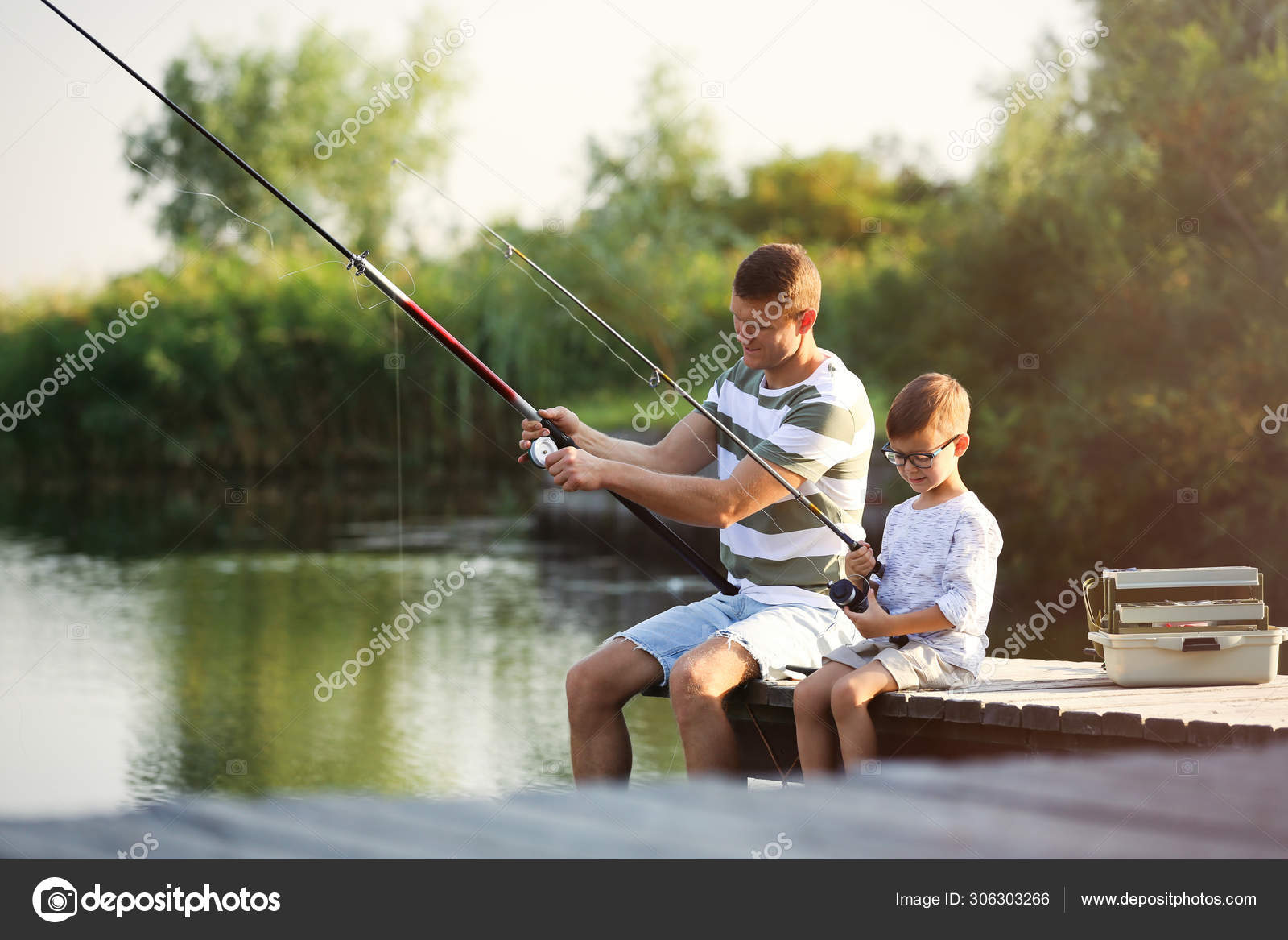 Dad and son fishing together on sunny day Stock Photo by
