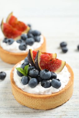 Beyaz ahşap masa üzerinde yaban mersini ve incir ile Tarts. Lezzetli hamur işleri