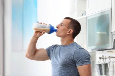 Atletik genç adam mutfakta protein shake içme