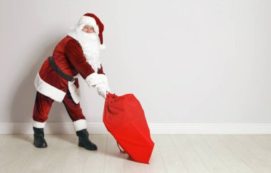 Gri duvara karşı hediyeler dolu çanta ile Otantik Noel Baba. Metin için alan
