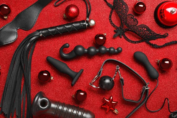 Conjunto de diferentes brinquedos sexuais e bolas de Natal no fundo vermelho, flat lay — Fotografia de Stock