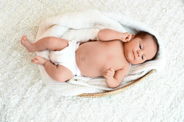 Cute little baby lying on knitted plaid in cradle, top view — Stock Photo, Image