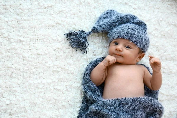 Mignon petit bébé en chapeau gris et plaid couché sur une couverture douce, vue de dessus. Espace pour le texte — Photo