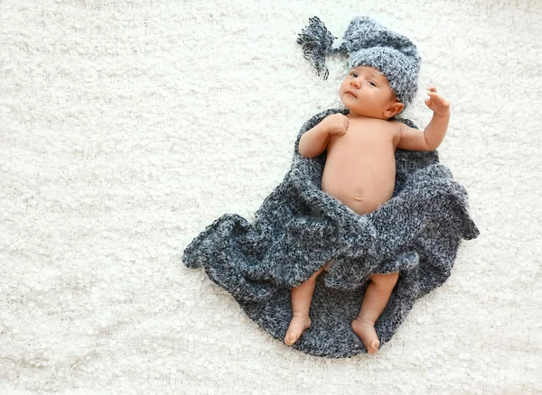Niedliches kleines Baby in grauer Mütze und Karo auf weicher Decke liegend, Draufsicht. Raum für Text — Stockfoto