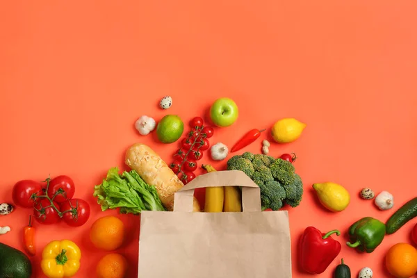 Stock image Paper bag with different groceries on coral background, flat lay