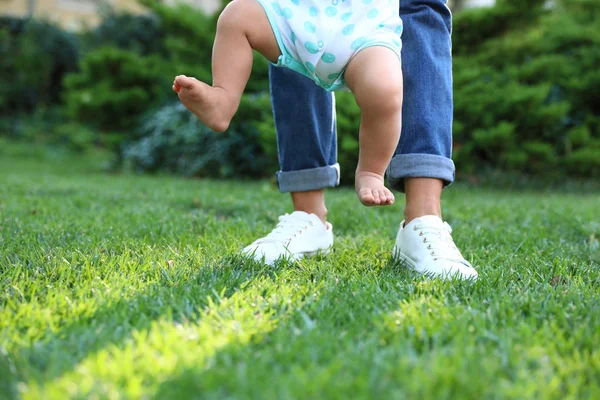 Sevimli küçük bebek yeşil çim açık havada onun dadı ile yürümeyi öğrenme, closeup — Stok fotoğraf