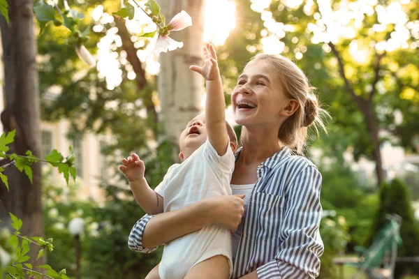 Teen Nanny med söt baby i parken på solig dag — Stockfoto