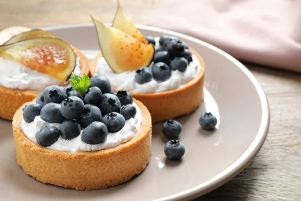 Placă de tarte cu afine și smochine pe masă de lemn, closeup. Produse de patiserie delicioase — Fotografie, imagine de stoc