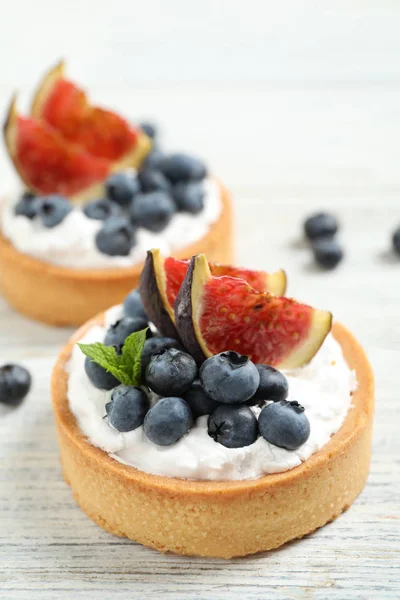 Tarts dengan blueberry dan ara di atas meja kayu putih. Kue-kue lezat — Stok Foto