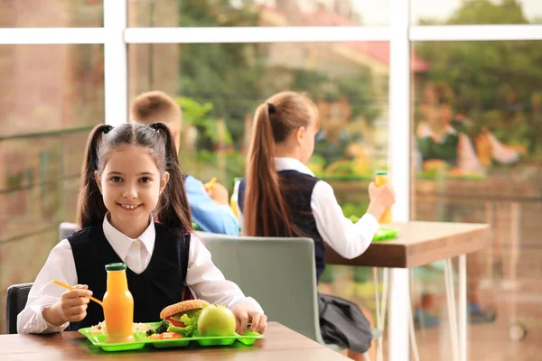 Ευτυχισμένο κορίτσι στο τραπέζι με υγιεινό φαγητό στο σχολικό κυλικείο — Φωτογραφία Αρχείου
