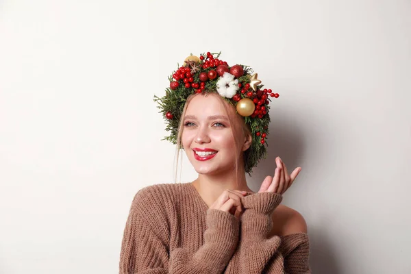 Όμορφη νεαρή γυναίκα φορώντας στεφάνι Χριστουγέννων σε λευκό φόντο — Φωτογραφία Αρχείου