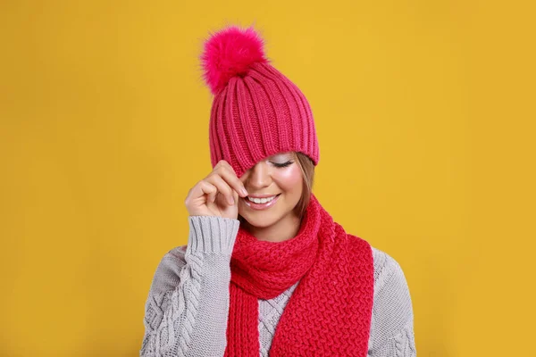 Lustige junge Frau in warmem Pullover, Schal und Hut auf gelbem Hintergrund. Wintersaison — Stockfoto