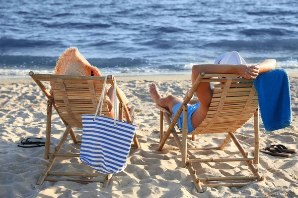 Jeune couple se détendre dans des chaises longues sur la plage près de la mer — Photo