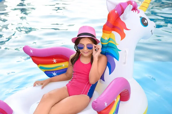 Glücklich süßes Mädchen auf aufblasbarem Einhorn im Schwimmbad — Stockfoto
