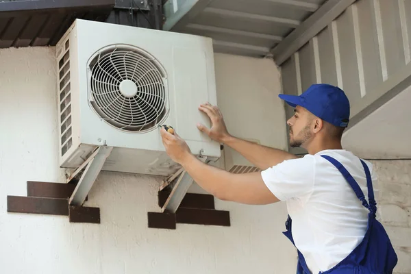 Técnico profissional mantendo ar condicionado moderno ao ar livre — Fotografia de Stock