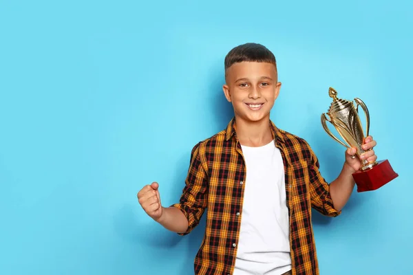 Gelukkige jongen met gouden winnende Cup op blauwe achtergrond — Stockfoto