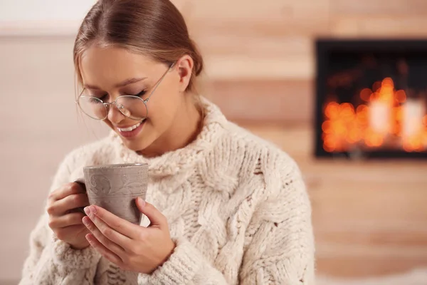 Krásná mladá žena s šálkem horkého drinku doma. Zimní atmosféra — Stock fotografie