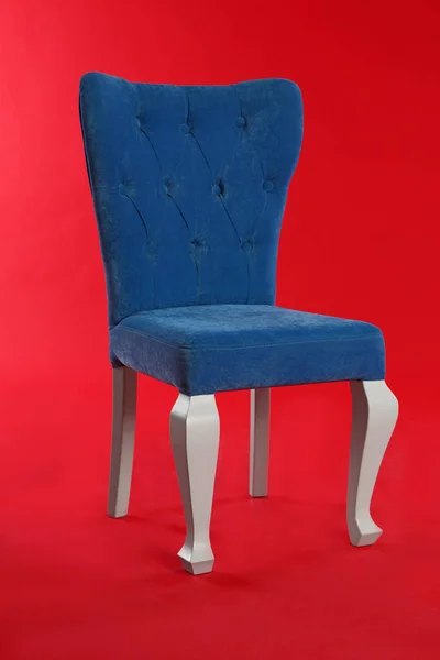 Stylowe niebieskie krzesło na czerwonym tle. Element wystroju wnętrz — Zdjęcie stockowe