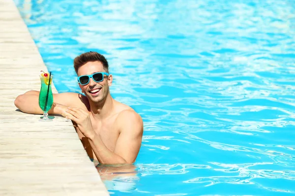Glücklicher junger Mann mit Cocktail im Schwimmbad — Stockfoto